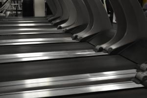 Close-up of the best treadmills under $300 aligned in a gym, focusing on the treadmill belts and machine quality.