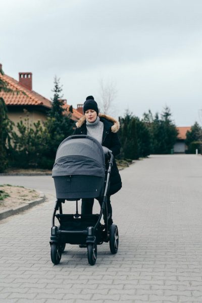 Woman pushing Nuna carriage. 