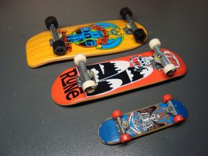 Three colorful skateboard of different sizes and designs, from a mini skateboard to larger skateboard, all lined up and ready for skateboarding action.