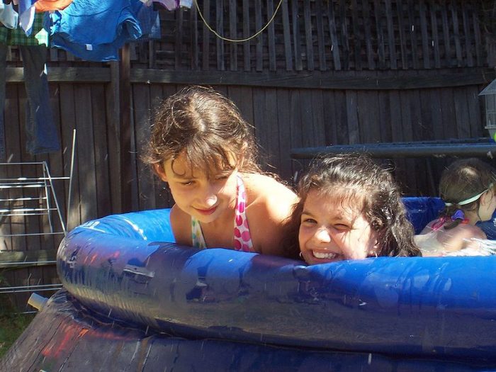 Two joyful girls, around 7, playing on a water slide—best summer moments.