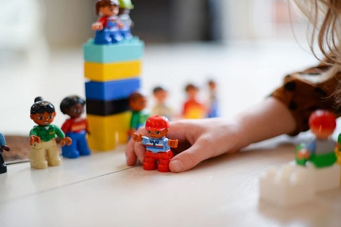 A girl’s hand playing with toy figures, showcasing the best imaginative play for 7-year-olds.