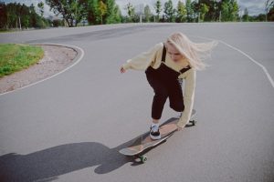 A girl on her longboard, trying to maneuver the longboard by finding her balance and momentum.