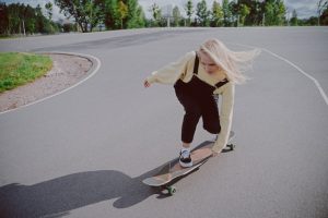 A girl on her longboard, trying to maneuver the longboard by finding her balance and momentum. 