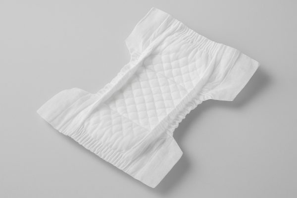 A premium overnight diaper opened to reveal a quilted, absorbent core and stretchable side panels on a neutral background.
