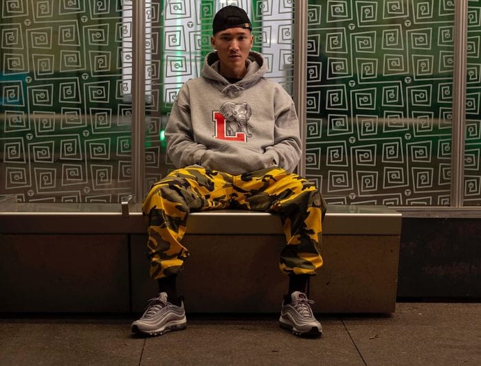 Image of male teenager sitting on a chair, wearing one of his best gifts, the gray hoodie jacket and yellow jogger.