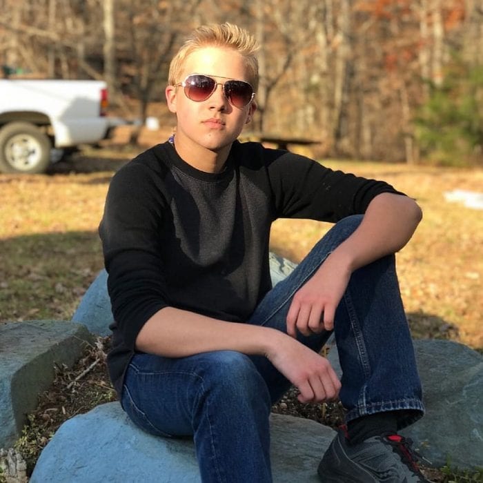 Image of a stylish male teenager confidently wearing one of his gifts, the sunglasses, showcasing a cool and trendy look. Perfect for capturing the essence of youthful fashion and self-expression.