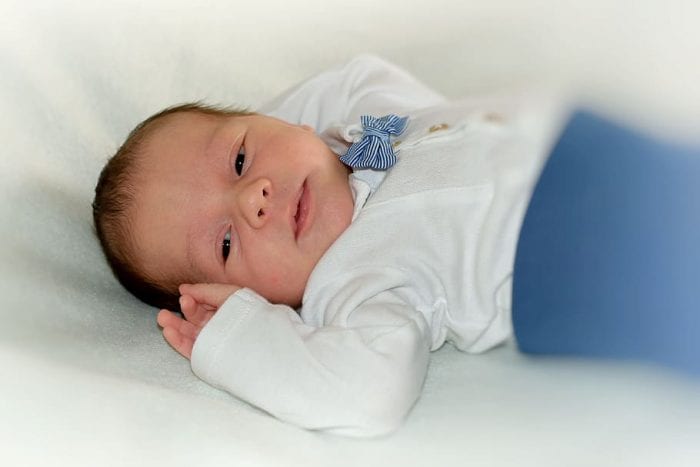 Baby names - A cute baby lying on a white cloth, surrounded by the charm of baby names that mean wish. 