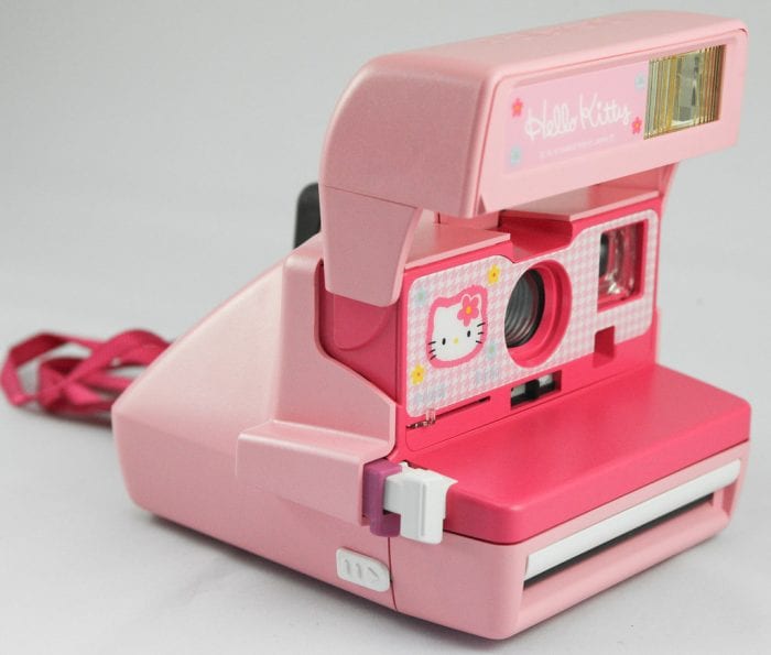A pink polaroid camera placed on the table.