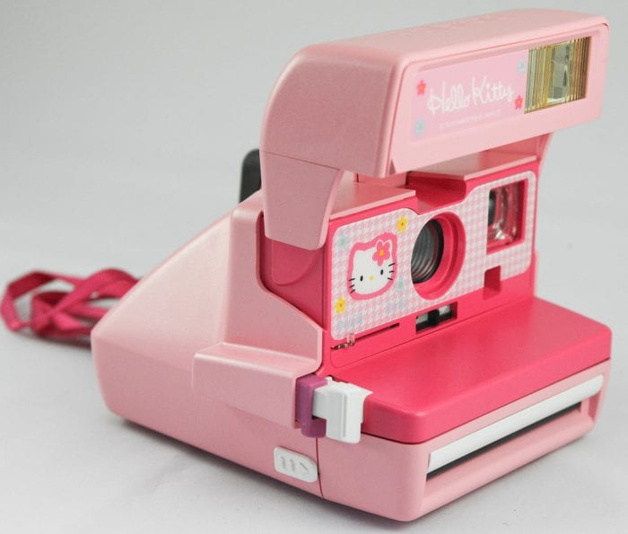 A pink polaroid camera placed on the table. 