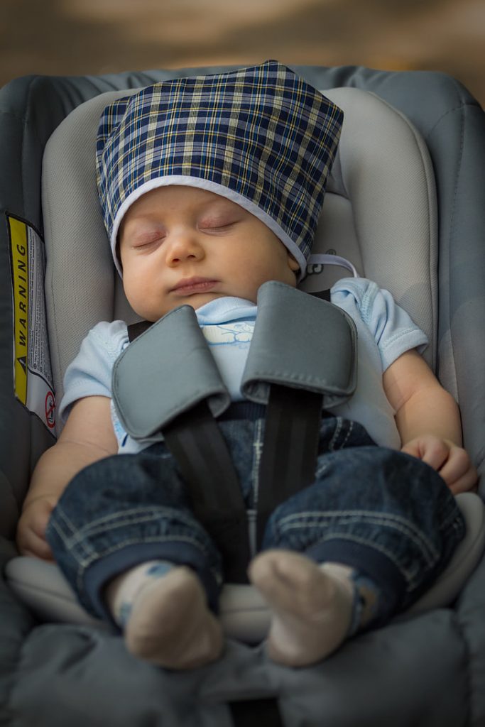 A cute little baby sleeping comfortably in a car booster.