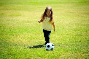 A kid playing in soccer field with smile in her face. A ball can be one of the best gifts for 8-year-olds.