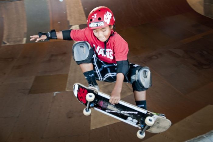 A kid with red skateboard helmet rides his best skateboard for beginner confidently.