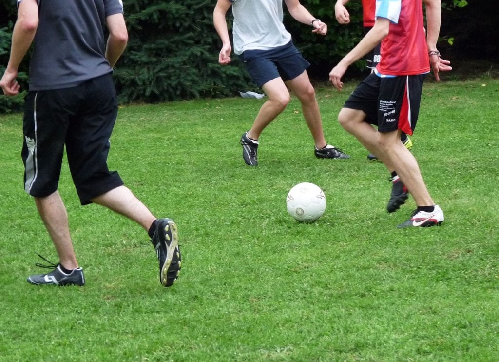 A group of people playing sports with a ball while wearing various shoes.