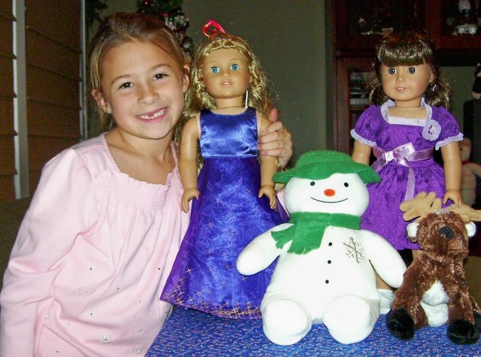 child showing off her baby doll in blue and baby doll in purple