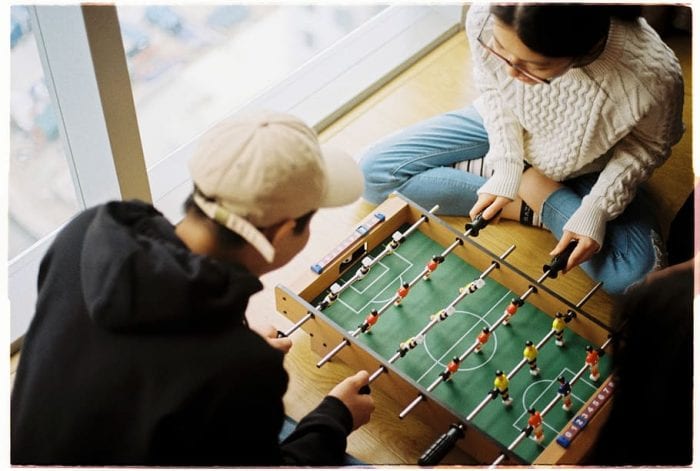 A man and a woman are having fun playing together football tables for kids