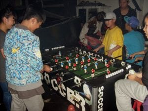 Group of people gathered around a foosball table, enjoying a competitive best football game.