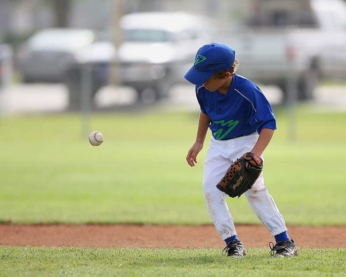 A boy wearing a catchers mitt while playing baseball on the field.