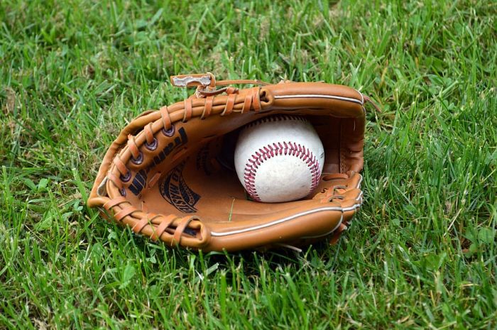 A photo of a glove and a baseball on the grass.