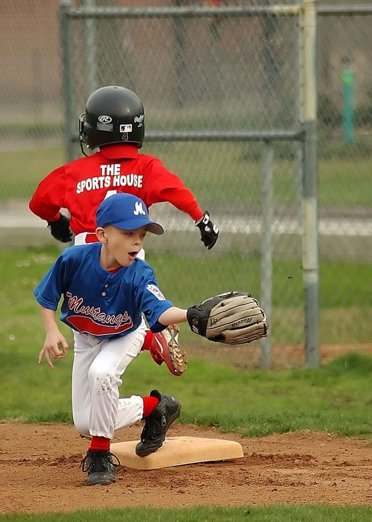 A boy using a youth catchers mitt while playing baseball on the field.