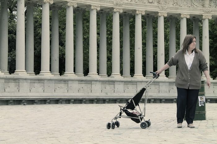 A woman is holding a stroller for children.