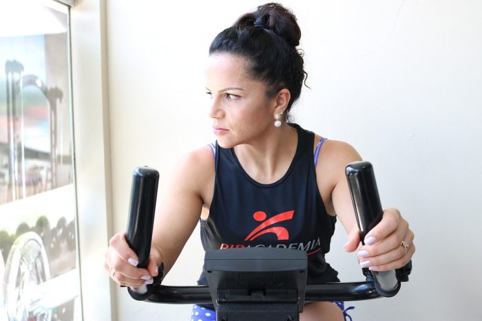 Woman working out using elliptical machine to burn belly fat. This is a good way to burn your calories as well. 