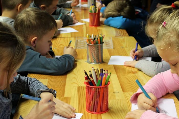 Children in school do their best artwork activity together using their best colored pens.