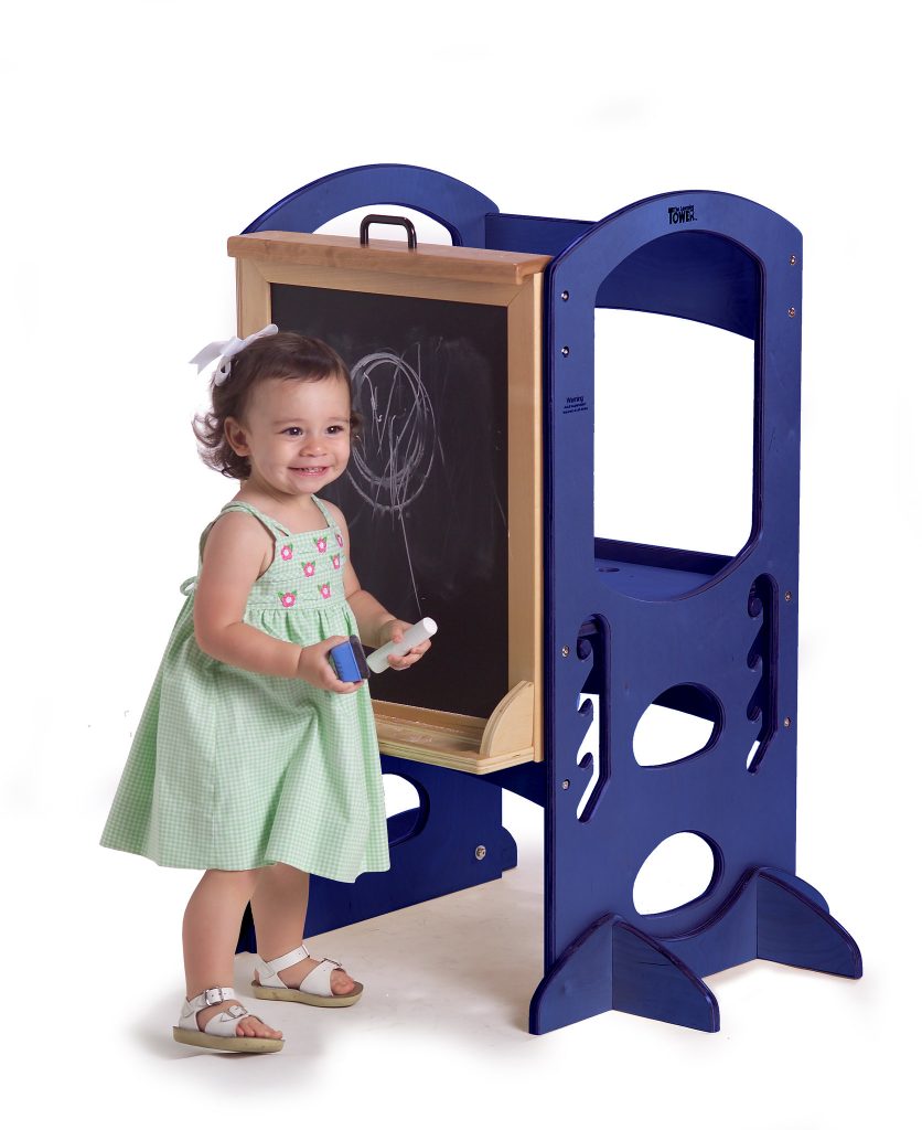A toddler wearing her best green dress happily used her easel for toddlers while doing her drawing. This high-quality easel makes the practice of writing skills so much better. 