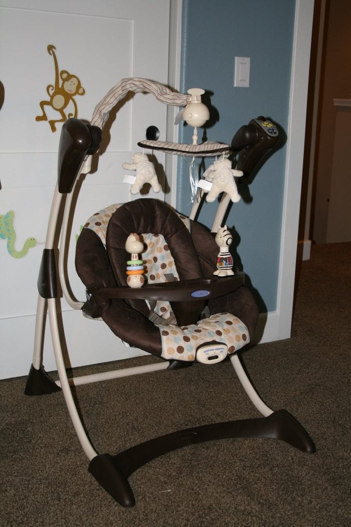 A brown and elegant baby swing is placed in the corner of the room.