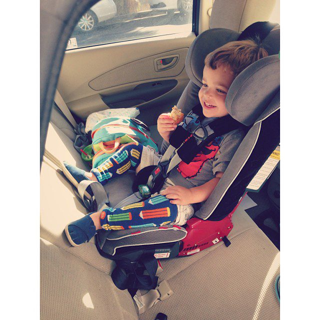 The boy is sitting on the carrier while holding a food.