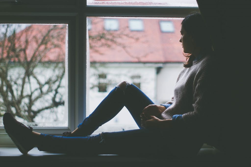 Image depicts a woman looking out the window and breathing in the fresh air. Using humidifiers is one of the best ways to bring clean air in your room.