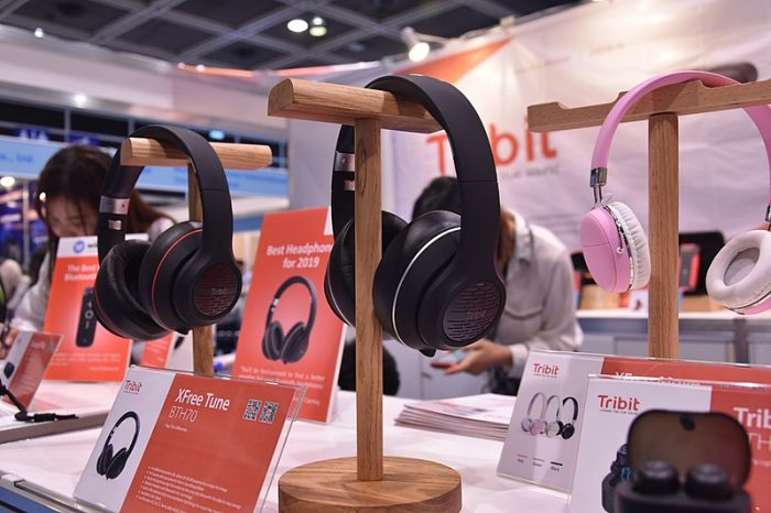 Many different headphones of different colors and features. it is also placed on a stand made specifically for these earphones