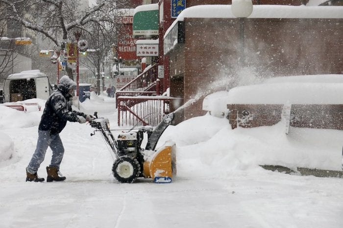 a man is doing his best on ridding the snow using the snow blower on a snowy morning