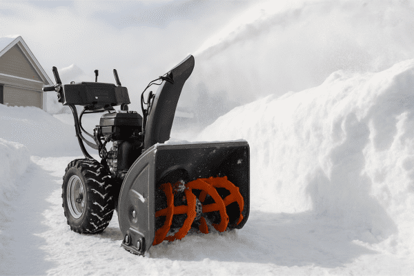 Heavy-duty snow blower clearing deep snow, large wheels, and dynamic snow discharge.