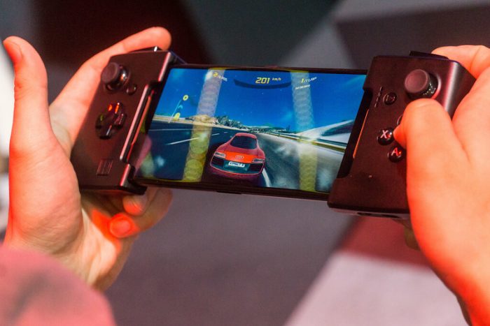A person playing car racing on their phone. Their phone has attachments that make playing easier and more convenient.