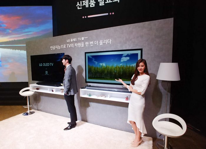 Two people presenting two OLED televisions. The Two OLED Televisions are out of this world