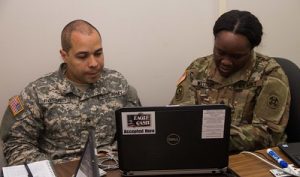 Two military personnel using a rugged laptop. 