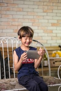 Cute kid sitting on a bench smiling and having fun playing using her best product for entertainment.