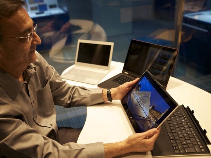 The man in glasses shows best smiles while looking at the image in the computer. 