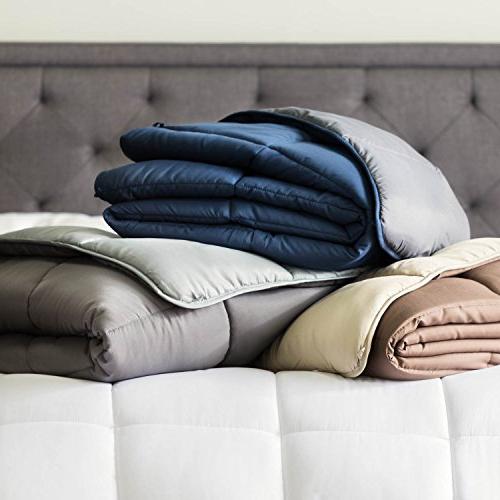 Perfect Down Comforter: An assortment of down duvets in neutral and dark blue hues, folded atop a bed to display their varying shades and thicknesses.