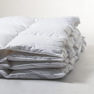 Perfect Down Comforter: A stack of fluffy down duvets piled high, showcasing the plush layers and luxurious texture. Each comforter promises warmth and comfort, beckoning with the promise of a cozy retreat.