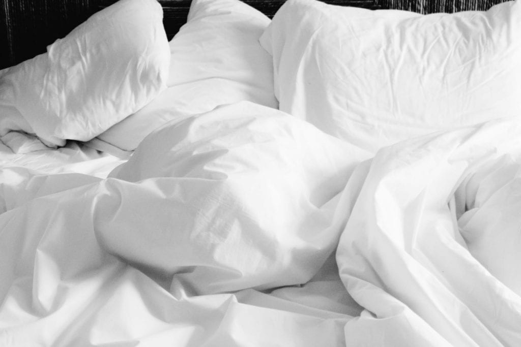 Perfect Down Comforter: An image of a bed with plush white comforters arranged in a welcoming, disheveled manner, inviting a sense of relaxation and rest. The soft folds of the fabric suggest a comfortable haven for unwinding after a long day.