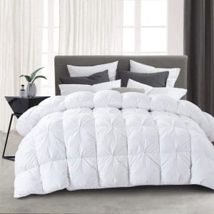 Perfect Down Comforter: A stylish bedroom featuring a plush down duvet in white, with tufted details, set against a modern grey upholstered bed frame. The bed's inviting appearance is enhanced by the soft light filtering through the room, highlighting the comforter's texture.