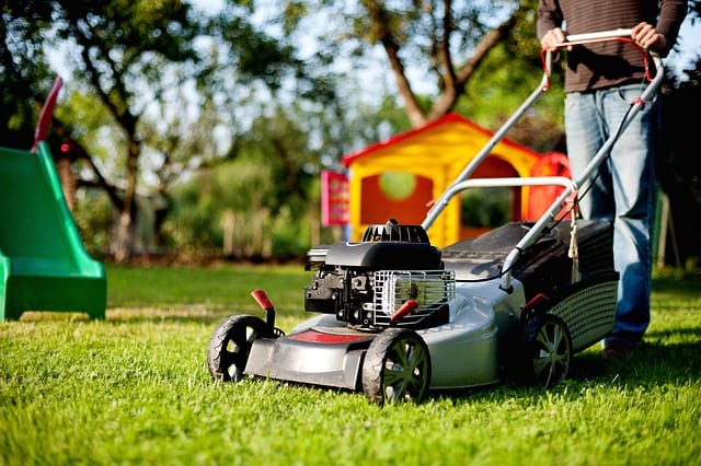 Man using a reel mower to maintain his lawn in the backyard. The reel mower offers convenient lawn care anytime. Using a reel mower is easy. Big reel mower.