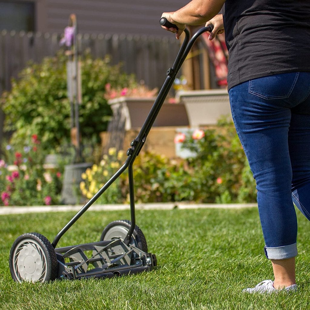 A reel mower being operated by a lady in the front yard. A manual reel mower doesn't need gas. A traditional reel mower is great. Black reel cutter. Slim reel trimmer.