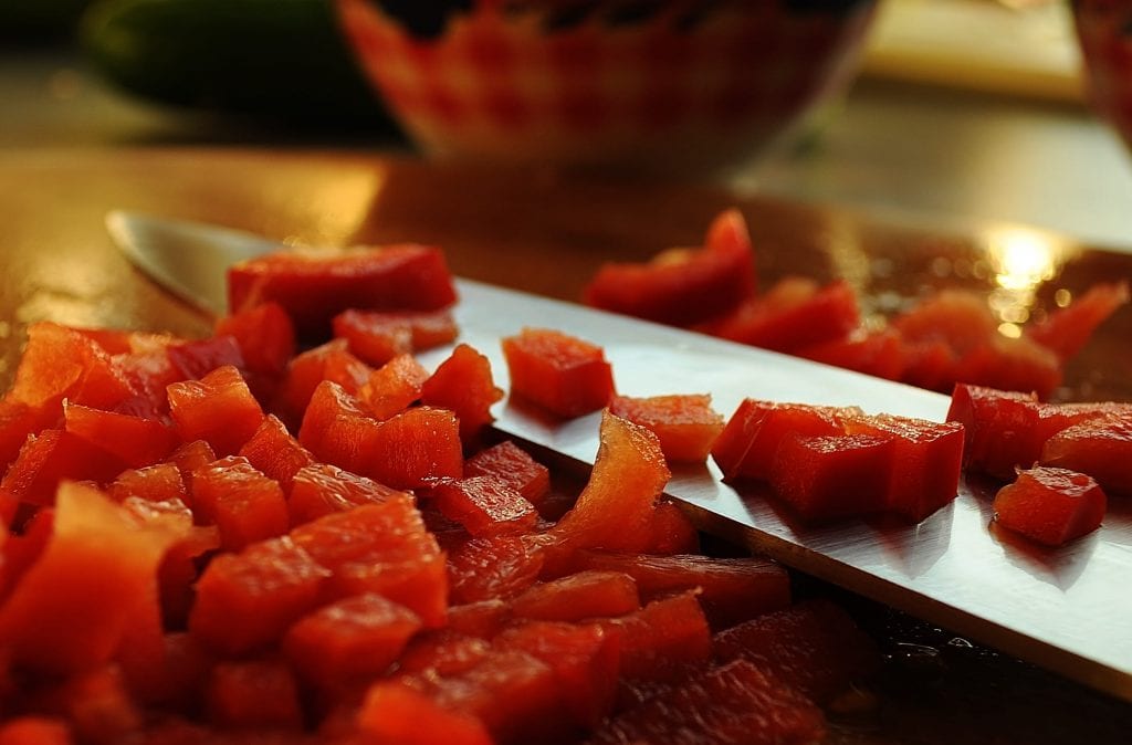 There is chef's best knife on a chopping board. There are also small pieces of meats. The meat looks fresh. 