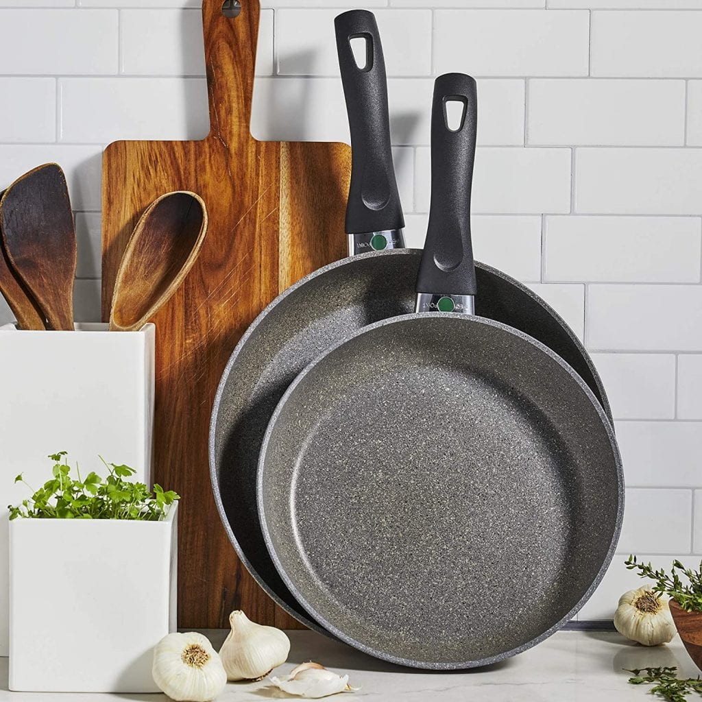 There are two cooking pans, three wooden spatula and ladle, and a big wooden chopping board. There are 3 below these kitchen tools. 