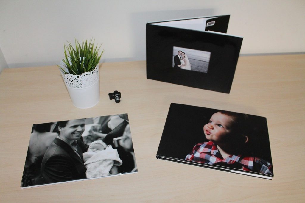 Cute and beautiful photos printed from polaroid camera placed on top of the table near a small potted plant. There's a baby photo and wedding photo.