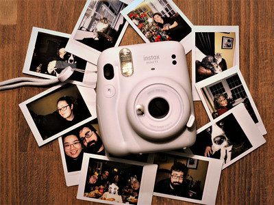 Fujifilm Instax Mini 11 Camera placed on top of the table surrounded with cute pictures. 