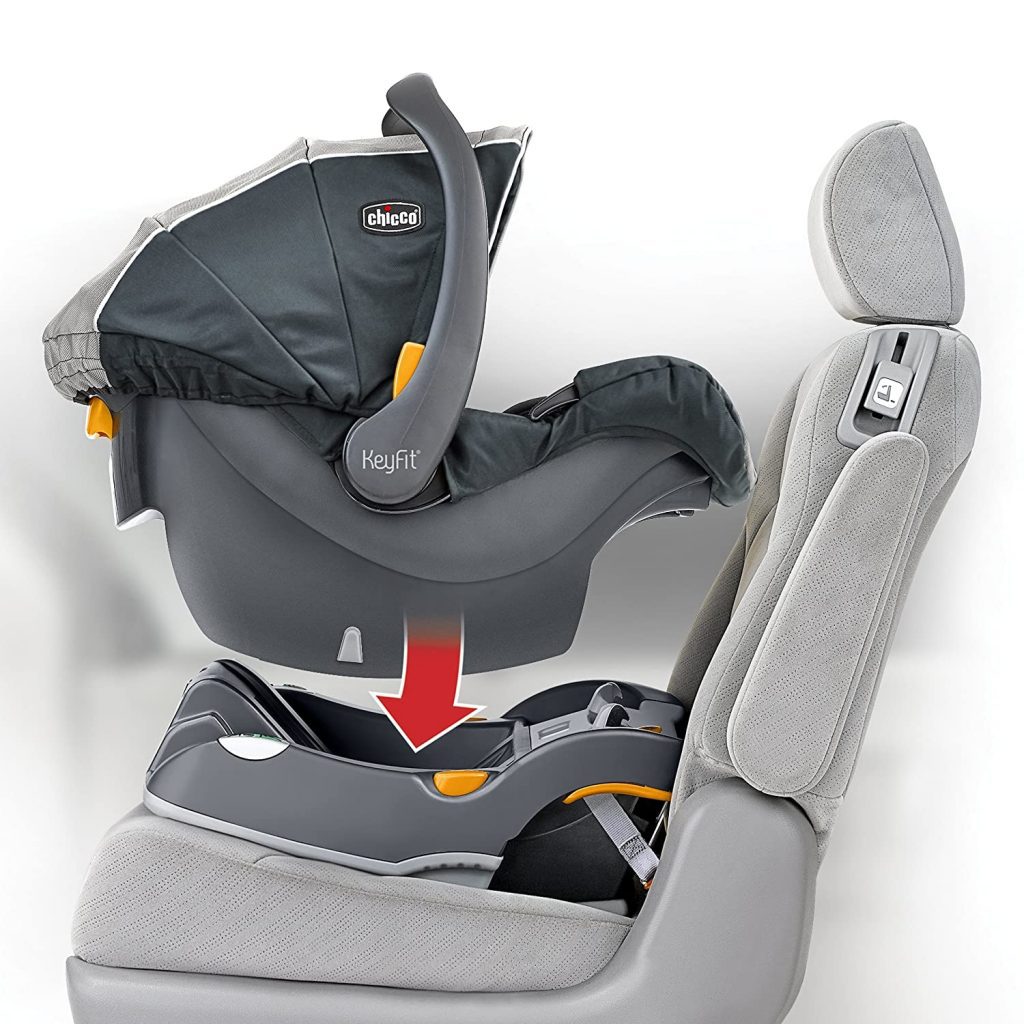 Best car seat for an infant: A Chicco KeyFit infant car seat, shown above its base, indicating how to click it into place with a red arrow. The seat and base are grey with orange accents, and are depicted next to a car's grey fabric seat. Perfect infant car seat.