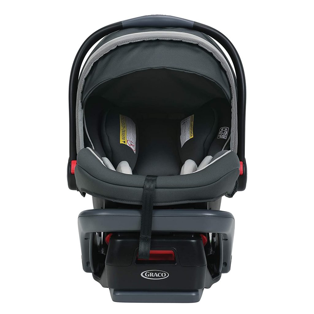 Best car seat for an infant: A joyful infant with a wide smile, secured in a black and gray rear-facing car seat with an adjustable canopy, inside a vehicle with a tan leather interior. Perfect infant car seat.